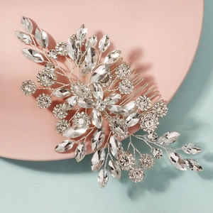 Detailed view of silver bridal hair comb with intricate floral rhinestones on pink tray
