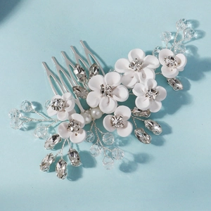Détail d'un peigne de mariée fait main avec fleurs blanches en céramique et cristaux