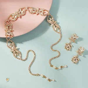 Détail d'une parure de mariée avec serre-tête fleuri en strass dorés et boucles d'oreilles