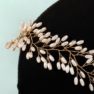 Detail eines handgefertigten Brauthaarbands mit weißen Perlen und Golddraht-Design