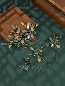 Detailed close-up of emerald green crystal gold hair comb set on a dark green background