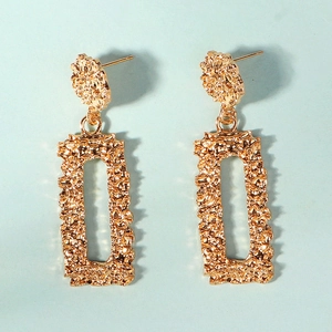 Vue détaillée de boucles d'oreilles dorées avec texture lave irrégulière et design ajouré