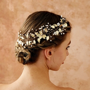 Dettaglio di tralcio per capelli dorato con perle e cristalli su acconciatura sposa