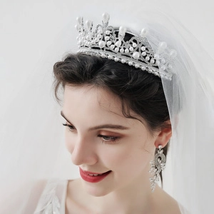 Detailed view of luxury bridal crown and dangling earrings set with pearls and rhinestones