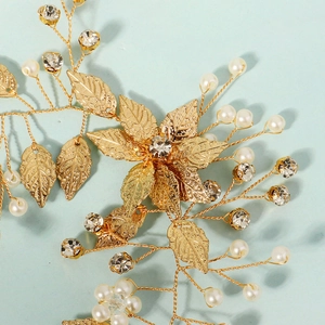 Dettaglio delle foglie in metallo dorato e perle bianche sul pettine per sposa