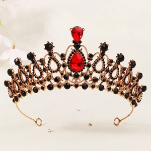 Detailed close-up of golden crown with red teardrop gems and black rhinestones