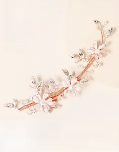 Close-up of handmade rose gold bridal hair clip with pink petals and pearls