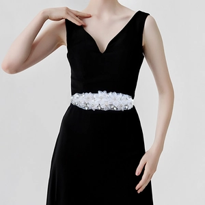 Gros plan de fleurs en tissu blanc faites main avec strass sur ceinture de mariée