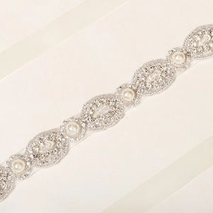 Detail of luxury bridal belt with pearls, rhinestones and silver beads on ivory ribbon