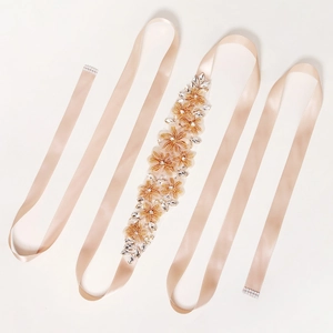 Détail de ceinture de mariée en satin champagne avec motifs floraux perlés faits à la main