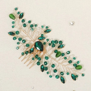 Dettaglio del pettine per capelli dorato con cristalli verde smeraldo e perline