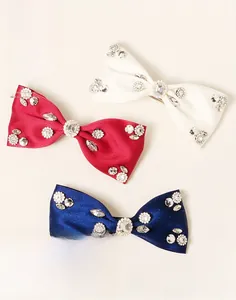 Detailed view of handmade bow hair clips in navy, red, and white with sparkling rhinestones