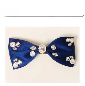 Detail of navy blue satin bow hair clip with sparkling rhinestones and crystal center