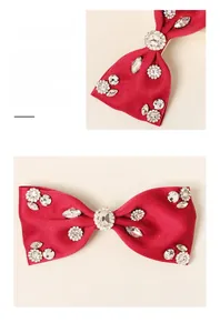 Detailed close-up of handmade red satin bow hair clip featuring sparkling rhinestones