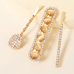 Three-piece gold hair clip set featuring sparkling rhinestones and amber cat eye stones