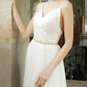 Detailed close-up of golden leaf bridal belt on elegant white satin wedding dress