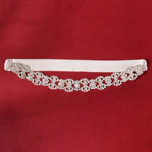 Detail of floral hollow rhinestone bridal garter with white elastic band on red background
