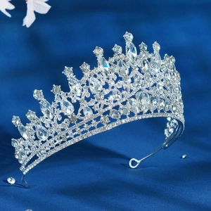 Close-up of a silver luxury bridal tiara with sparkling rhinestones on blue velvet