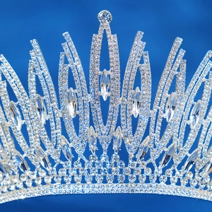 Macro shot of silver wedding crown with shimmering rhinestones and crystals on blue background
