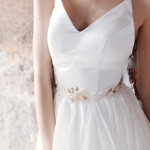Detail of luxury bridal belt with pearls, rhinestones and golden leaves on white satin