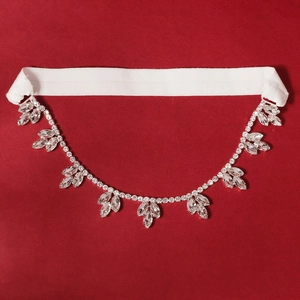 Detail of bridal garter with sparkling rhinestone leaf chain on white elastic band