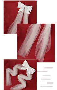 Detailed close-up of a white satin bow bridal veil with long flowing mesh on red silk