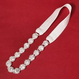 Close-up of sparkling bridal garter with luxury rhinestone flowers on red velvet