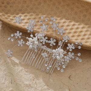 Macro detail of bridal hair comb featuring handmade crystal flowers and white pearls