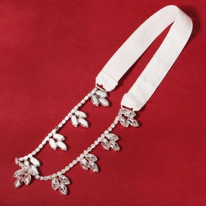 Macro detail of elastic bridal garter featuring sparkling leaf rhinestones on red background