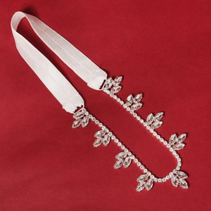 Macro shot of bridal rhinestone garter with silver leaf-shaped crystals on red background