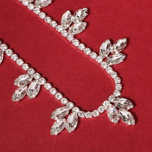 Sparkling crystal bridal garter with leaf-shaped rhinestones on a vibrant red background