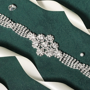 Luxurious silver bridal belt with intricate floral rhinestones on green background