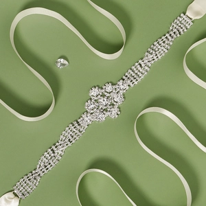 Elegant silver bridal belt with sparkling rhinestones and cream satin ribbon on green