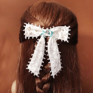 Détail d'une pince à cheveux nœud en satin blanc avec perles en cristal sur cheveux