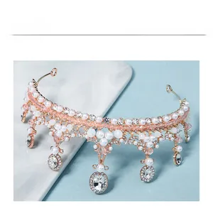 Close-up of rose gold bridal crown featuring white pearls and hanging teardrop crystals