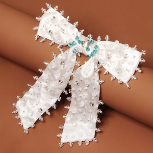 Détail de la pince à cheveux en satin blanc avec perles de cristal et pierre bleue