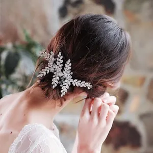 Detail eines silbernen Brauthaarkamms mit Kristallblättern in einer eleganten Hochsteckfrisur