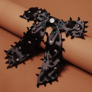 Détail d'une barrette nœud en soie noire avec cristaux bleus et strass étincelants