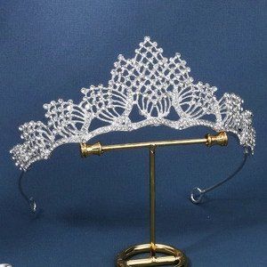 Detailed close-up of a silver tiara with white crystals and hollow alloy design on a stand