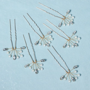 Close-up of gold U-shaped hair pins set with elegant white pearls and rhinestones
