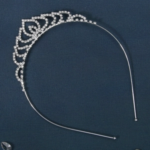 Macro detail of silver drop-shaped headband with heart crystal patterns on blue background