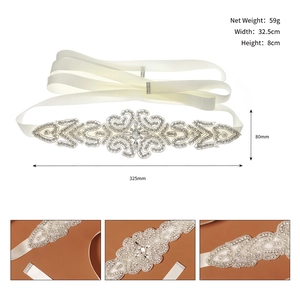 Detailed view of silver rhinestone bridal belt with elegant scroll patterns on ivory ribbon