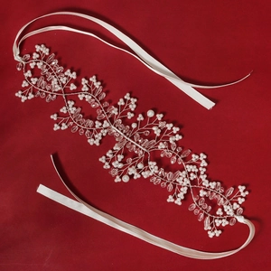 Close-up of handmade bridal headband with white beads and vine-shaped silver wire