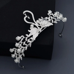 Macro detail of bridal tiara featuring silver swans, crystals, and white pearls on box