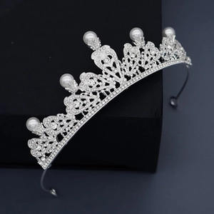 Detail view of silver crown with white crystals and pearls on elegant display stand