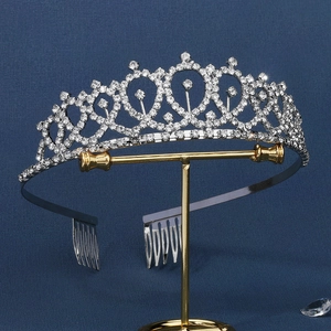 Detailed view of silver wedding crown with heart patterns on a gold display stand