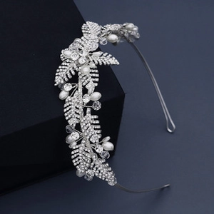 Détail d'un serre-tête de mariée argenté avec feuilles de cristal et perles sur support noir