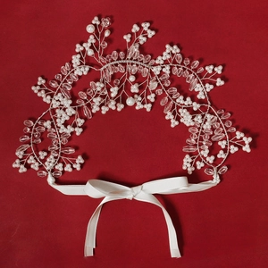 Exquisite handmade bridal headband with white pearls and crystals on a dark red background