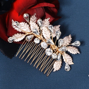 Close-up of golden leaf hair comb with crystals and red rose on blue background