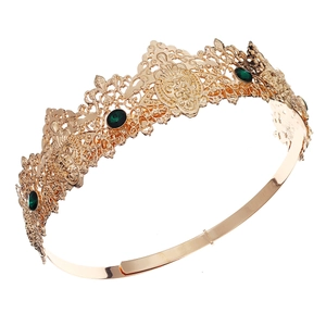 Detail of vintage gold crown featuring baroque floral patterns and green gemstones